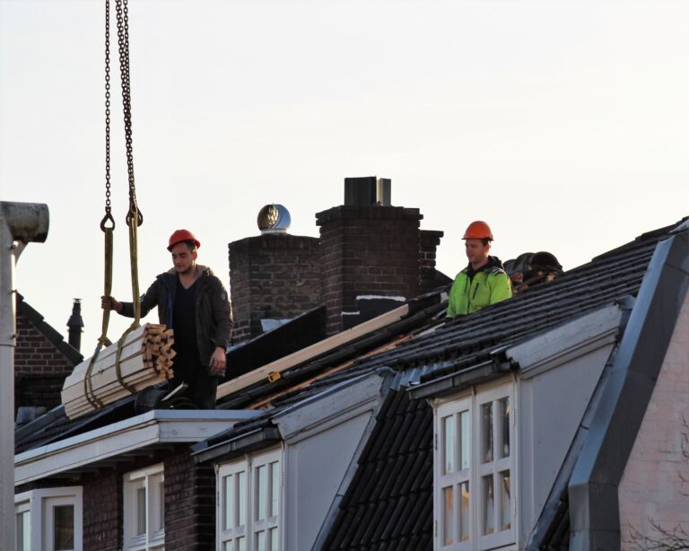 Workers operate on a rooftop under construction in the Netherlands, showcasing teamwork and safety.